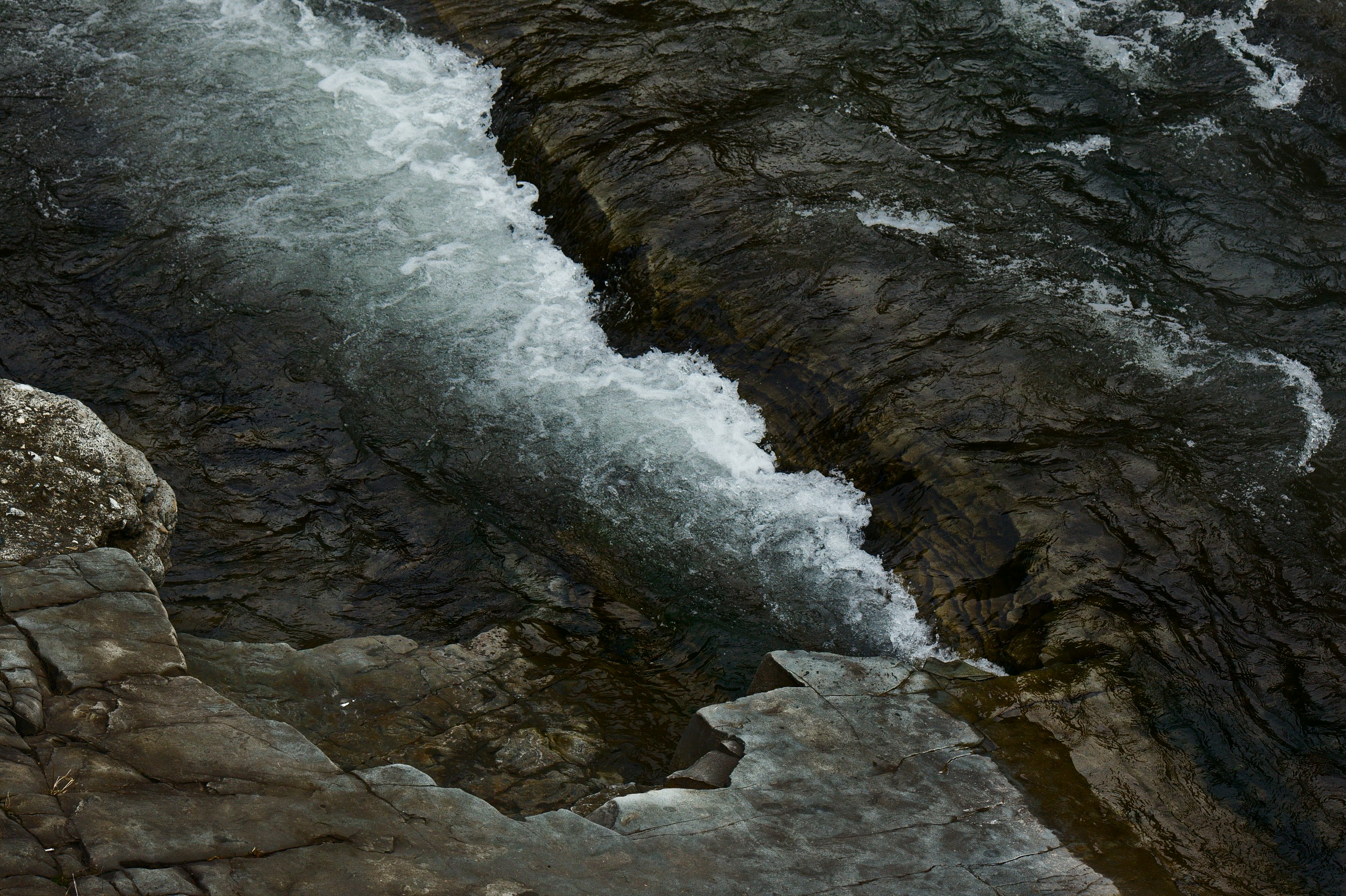 bird's eye view of water crashing boulders